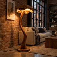 Floor lamp with a winding wooden stem and a wavy mushroom cap shade in an industrial loft living room with exposed brick