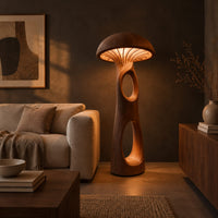 Mushroom floor lamp with a domed cap and tall carved stem in a dark living room at golden hour