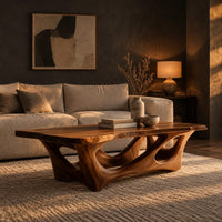 Natural edge coffee table with an open branching wood base in a dark living room at golden hour
