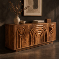Corner detail of sideboard with nested arch carving and spiral motifs on four doors beside wood, brass and linen samples