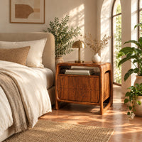 Nightstand with an open top cubby and a looped side frame in a bright bedroom with arched windows and plants