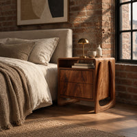Nightstand with an open top niche and sculpted loop shaped sides in an industrial loft bedroom with exposed brick