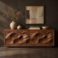 Corner detail of low sideboard with four carved wave relief panels on a plinth base beside wood, brass and linen samples