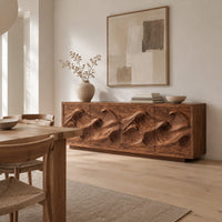 Low sideboard with four carved wave relief panels on a plinth base in a Scandinavian dining room with white walls