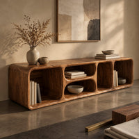 Corner detail of low tv stand with soft edges and a stacked pair of oval cubbies beside wood, brass and linen samples