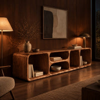 Low tv stand with soft edges and a stacked pair of oval cubbies in an evening living room with walnut wall paneling