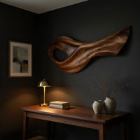 Open eye swoosh wooden wall sculpture above a desk in a dark study corner