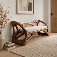 Wooden bench with a pale cushioned seat and an organic open frame in a Scandinavian entryway with white walls