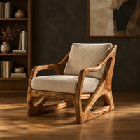 Armchair with a sculpted open wood frame and cream cushions in a dark studio against a charcoal plaster wall