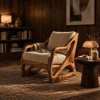Armchair with a sculpted open wood frame and cream cushions in an evening living room with walnut wall paneling
