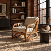 Armchair with a sculpted open wood frame and cream cushions in an industrial loft living room with exposed brick