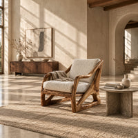 Armchair with a sculpted open wood frame and cream cushions in a bright open plan living room