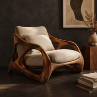 Corner detail of open frame wooden lounge chair with thick sculpted loops and cream cushions beside wood, brass and linen samples