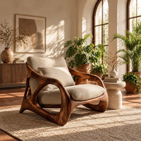 Open frame wooden lounge chair with thick sculpted loops and cream cushions in a bright living room with arched windows and plants