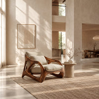Open frame wooden lounge chair with thick sculpted loops and cream cushions in a bright open plan living room