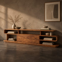 Corner detail of low tv stand with open cubbies, a wide center panel and stacked end shelves beside wood, brass and linen samples