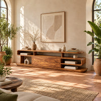 Low tv stand with open cubbies, a wide center panel and stacked end shelves in a bright living room with arched windows and plants