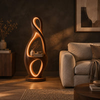 Tall floor lamp shaped as a looping figure eight with a small shelf in a dark living room at golden hour