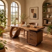 Desk with an open loop leg and a three drawer pedestal in a bright home office with arched windows and plants