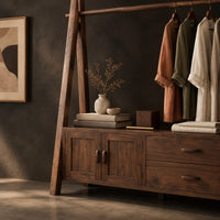 Corner detail of open rail wardrobe with slanted side posts and a low cabinet base beside wood, brass and linen samples