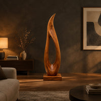 Tall teardrop sculpture with an open center and a pointed tip in a dark living room at golden hour