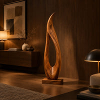 Tall teardrop sculpture with an open center and a pointed tip in an evening living room with walnut wall paneling