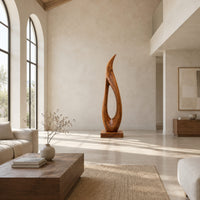 Tall teardrop sculpture with an open center and a pointed tip in a bright open plan living room