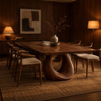 Dining table with a slab top and an open teardrop pedestal in an evening dining room with walnut wall paneling
