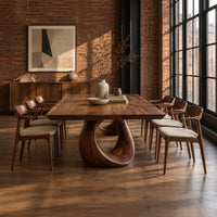 Dining table with a slab top and an open teardrop pedestal in an industrial loft dining room with exposed brick
