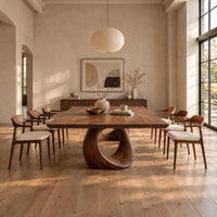 Dining table with a slab top and an open teardrop pedestal in a bright open plan dining room
