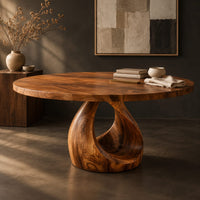 Corner detail of round dining table with an open teardrop loop pedestal base beside wood, brass and linen samples