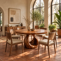 Round dining table with an open teardrop loop pedestal base in a bright dining room with arched windows and plants