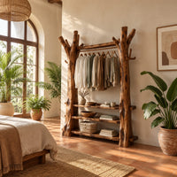Open wardrobe with tree trunk posts, a hanging rail and three plank shelves in a bright bedroom with arched windows and plants