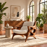 Openwork wooden lounge chair with hollowed arms and splayed legs in a bright living room with arched windows and plants