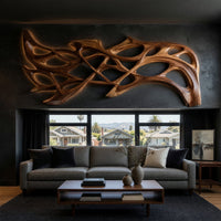 Hand carved organic openwork wooden wall sculpture on a dark charcoal plaster wall
