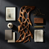 Detail of hand carved organic openwork wooden wall sculpture beside wood, brass and linen samples