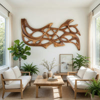 Hand carved organic openwork wooden wall sculpture in a bright sunroom with green plants