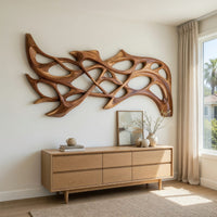 Hand carved organic openwork wooden wall sculpture above a light oak sideboard in daylight