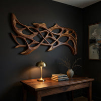 Hand carved organic openwork wooden wall sculpture above a desk in a dark study corner
