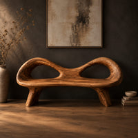 Organic wooden bench with a raised rim, two oval cutouts and tapered legs in a dark studio against a charcoal plaster wall