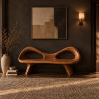 Organic wooden bench with a raised rim, two oval cutouts and tapered legs in a dark entryway at golden hour