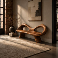 Organic wooden bench with a raised rim, two oval cutouts and tapered legs in an industrial loft entryway with exposed brick
