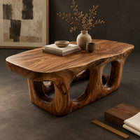 Corner detail of coffee table with round porthole openings in a solid base beside wood, brass and linen samples