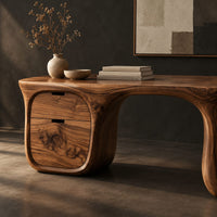 Corner detail of desk with a flowing top, two drawer block and open loop leg beside wood, brass and linen samples