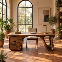 Desk with a flowing top, two drawer block and open loop leg in a bright home office with arched windows and plants