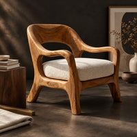 Corner detail of open back chair with curved crest rail and splayed legs beside wood, brass and linen samples
