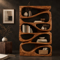 Corner detail of stacked bookshelf with flowing teardrop shaped openings beside wood, brass and linen samples