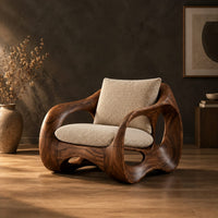 Wraparound lounge chair with open loop sides and arched base in a dark studio against a charcoal plaster wall