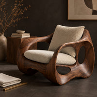 Corner detail of wraparound lounge chair with open loop sides and arched base beside wood, brass and linen samples