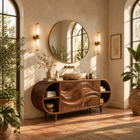Oval vanity cabinet on tapered legs with carved wave doors and open end shelves in a bright bathroom with arched windows and plants